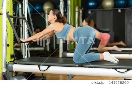 Young woman doing abdominal exercises on reformer Young woman doing abdominal exercises on reformer 141956269
