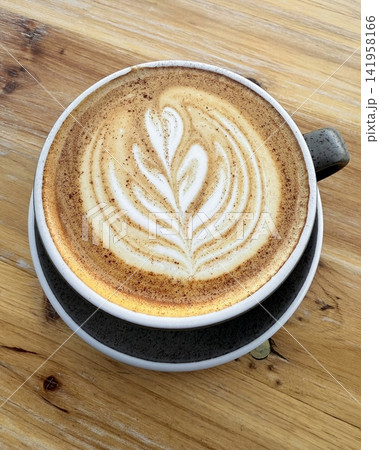 A beautifully crafted latte, featuring creamy foam art on top of rich espresso. Perfect for coffee-related projects, this image captures the warmth and inviting nature of a classic cafe experience. A beautifully crafted latte, featuring creamy foam art on top of rich espresso. Perfect for coffee-related projects, this image captures the warmth and inviting nature of a classic cafe experience. 141958166