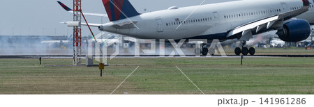 Close-up of passenger aircraft touching down at Amsterdam Schiphol with runway tire smoke and heat haze Close-up of passenger aircraft touching down at Amsterdam Schiphol with runway tire smoke and heat haze 141961286