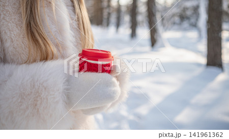 Woman holding coffee cup in winter park Woman holding coffee cup in winter park 141961362