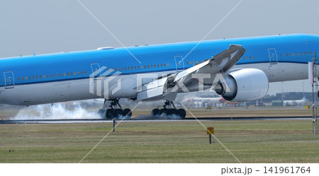 Close-up of passenger aircraft touching down at Amsterdam Schiphol with runway tire smoke and heat haze. Close-up of passenger aircraft touching down at Amsterdam Schiphol with runway tire smoke and heat haze. 141961764