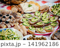Traditional festive table with homemade appetizers, sandwiches with cucumber and dill, sliced bread, fish, olives and fresh salads. Abundant homemade food served for a family celebration or holiday 141962186