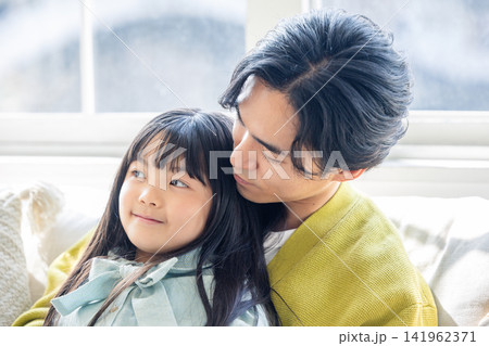 リビングで父親に寄り添い優しく微笑む女の子 リビングで父親に寄り添い優しく微笑む女の子 141962371