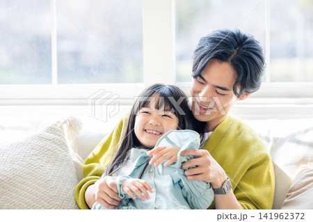 父親の膝の上に座る笑顔の娘 父親の膝の上に座る笑顔の娘 141962372