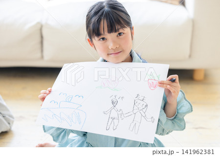 自分で描いた家族の絵を嬉しそうに見せる笑顔の女の子 自分で描いた家族の絵を嬉しそうに見せる笑顔の女の子 141962381