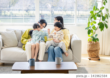 日当たりの良いリビングのソファで仲良く談笑する4人家族 141962384