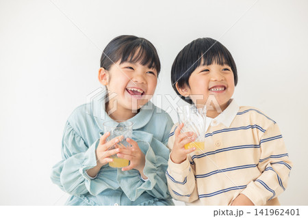 コップを持って楽しそうに飲み物を味わう男の子と女の子 コップを持って楽しそうに飲み物を味わう男の子と女の子 141962401