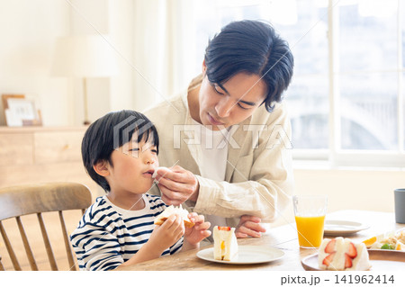 朝食のテーブルで息子の口元を優しく拭う父親 141962414