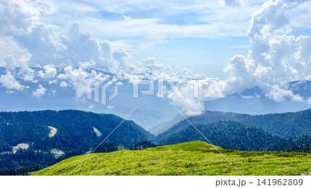 Lush alpine meadow overlooking misty mountain valley Lush alpine meadow overlooking misty mountain valley 141962809