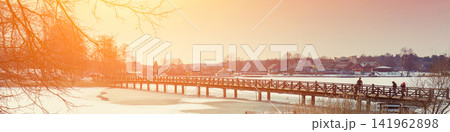 Winter frozen lake with wooden bridge at sunset light 141962898