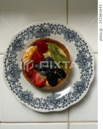 A delightful fruit tart with a buttery, flaky crust filled with creamy custard and topped with an array of fresh, vibrant fruits. Perfectly balanced between sweet and tangy, making it irresistible 141963643