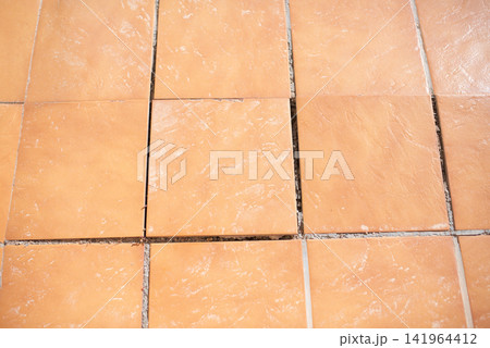 Damaged terracotta floor tiles with empty wide gaps renovation required top view 141964412