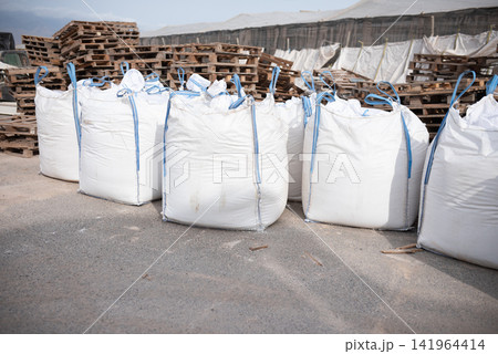Big white industrial bulk bags with wooden pallets at outdoor warehouse Big white industrial bulk bags with wooden pallets at outdoor warehouse 141964414
