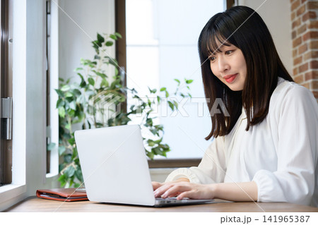 オフィスでノートパソコンを使う若いビジネスウーマン オフィスでノートパソコンを使う若いビジネスウーマン 141965387