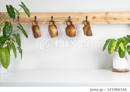various wooden cup hanging on a wooden bar and plant pot white counter surface various wooden cup hanging on a wooden bar and plant pot white counter surface 141966348