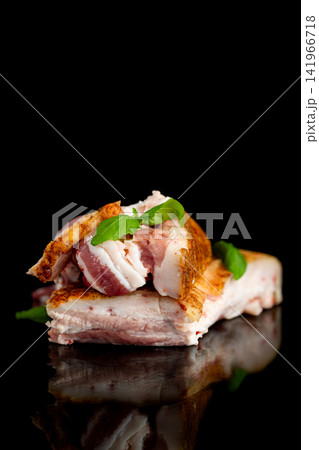 Rustic pork lard slices with fresh basil on dark reflective surface Rustic pork lard slices with fresh basil on dark reflective surface 141966718