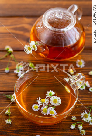 Traditional chamomile tea with fresh flowers and teapot on wooden background Traditional chamomile tea with fresh flowers and teapot on wooden background 141966735