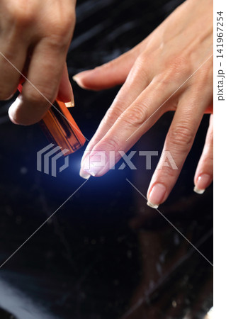A woman's hand during a manicure. A woman getting a manicure. A manicurist is doing a client's nails at a nail salon. Manicure services. Nail art. Beauty salon. 141967254