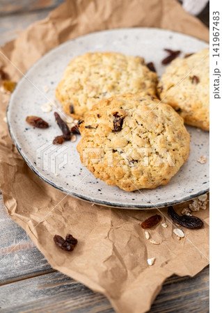 Homemade pastry. Crunchy biscuits. Traditional sweets with raisins cereal served on plate. Healthy meal on craft paper background. Homemade pastry. Crunchy biscuits. Traditional sweets with raisins cereal served on plate. Healthy meal on craft paper background. 141967483