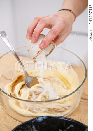 Home cooking. Adding ingredient. Female chef hand pouring measuring sugar portion in glass bowl with sweet caramel cream pastry mass. 141967532