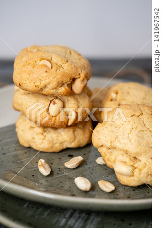 Peanut treat. Home pastry. Golden round fluffy cookies stack served on plate with scattered ingredient. Yummy baked crispy dessert. Peanut treat. Home pastry. Golden round fluffy cookies stack served on plate with scattered ingredient. Yummy baked crispy dessert. 141967542