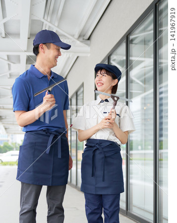 用具を持って笑顔で会話する清掃スタッフ 用具を持って笑顔で会話する清掃スタッフ 141967919