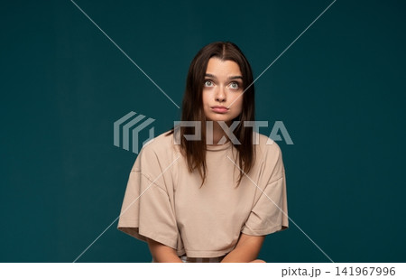 Young woman looking up with a surprised and confused facial expression, wondering about a new idea or question Young woman looking up with a surprised and confused facial expression, wondering about a new idea or question 141967996