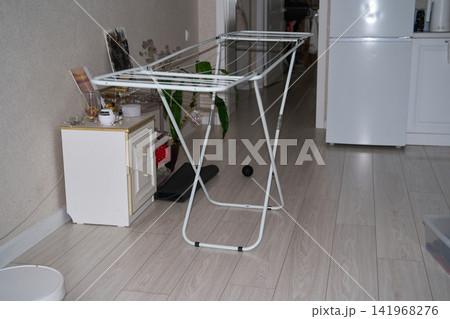 Foldable Drying Rack Standing Indoors Beside Refrigerator And Storage Cabinet In Small Home 141968276