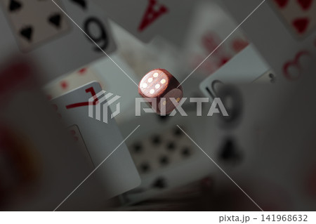 Wooden die in motion surrounded by playing cards. Wooden die in motion surrounded by playing cards. 141968632