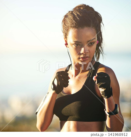 Woman, boxer and fists for outdoor exercise with earphones or streaming music, podcast or subscription. Female person, fighter and athlete for fitness routine in nature park or playlist, audio or fit Woman, boxer and fists for outdoor exercise with earphones or streaming music, podcast or subscription. Female person, fighter and athlete for fitness routine in nature park or playlist, audio or fit 141968912