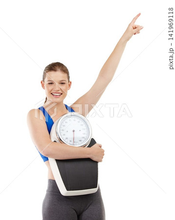 Portrait of girl, pointing and scale in studio background for measurement, smile and excited for results of diet. Female person, body and care for calories target or goals, weight loss and mockup 141969118