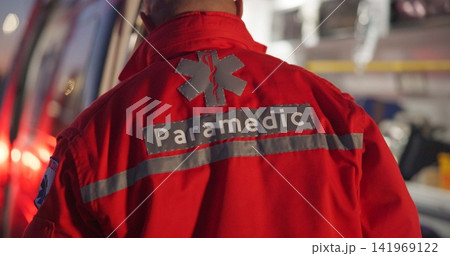Back, man and paramedic walking to ambulance for emergency, ems service and healthcare in city. Rear view, medical professional and doctor outdoor at night for first aid, rescue operation and work 141969122