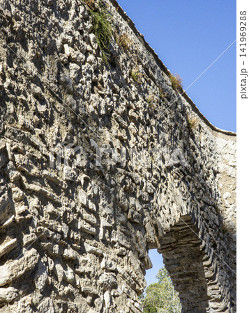 Close up view of ancient aqueduct stonework showing texture and arch in a historical location under clear sky Close up view of ancient aqueduct stonework showing texture and arch in a historical location under clear sky 141969288