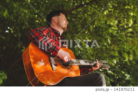 Man with Eyes Closed Playing Acoustic Guitar Man with Eyes Closed Playing Acoustic Guitar 141970211