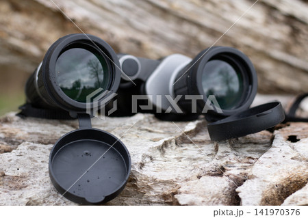 Black binoculars on a fallen tree, travel concept 141970376