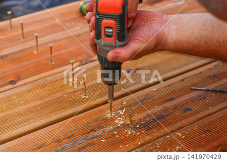 Man nailing the wooden boards to fix the terrase 141970429