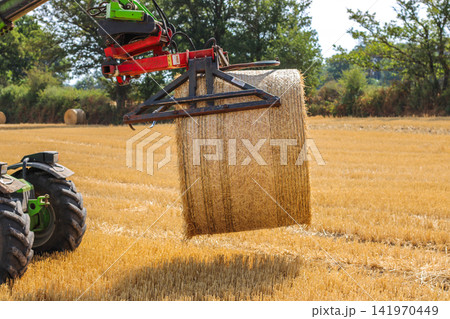 Tractor collecting cut grass in rural field 141970449