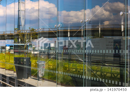 Modern glass building facade reflecting clouds Modern glass building facade reflecting clouds 141970450