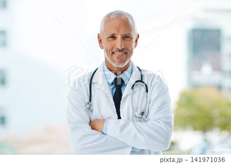 Doctor, happy and portrait of mature man in a hospital at a cardiology clinic with arms crossed. Professional, medical employee and stethoscope with healthcare, surgeon and cardiologist consultant 141971036