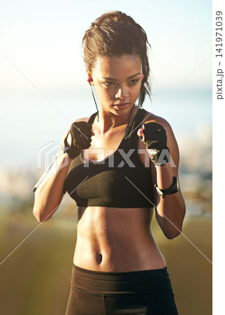 Woman, athlete and fists for boxing outdoor or earphones as exercise music, martial arts or fitness. Female person, streaming and subscription playlist or wellness punch as audio, health or training Woman, athlete and fists for boxing outdoor or earphones as exercise music, martial arts or fitness. Female person, streaming and subscription playlist or wellness punch as audio, health or training 141971039