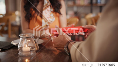 Love, couple or hands in restaurant with gift, romantic surprise or bonding in anniversary celebration. Loyalty, date or people with present, special moment or connection in relationship engagement. 141971065