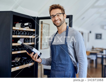 Bottle, cafe and portrait of man at wine shelf for selection, choice and hospitality. Smile, alcohol and restaurant sommelier, waiter or small business owner checking drinks for service quality. Bottle, cafe and portrait of man at wine shelf for selection, choice and hospitality. Smile, alcohol and restaurant sommelier, waiter or small business owner checking drinks for service quality. 141971068