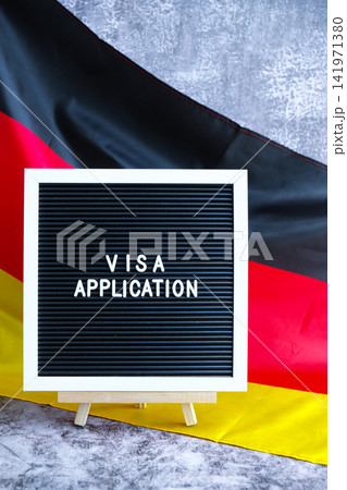 Letter board text VISA APPLICATION National symbol of Germany. German wave silky flag background. Temporary work permit employment migration Letter board text VISA APPLICATION National symbol of Germany. German wave silky flag background. Temporary work permit employment migration 141971380