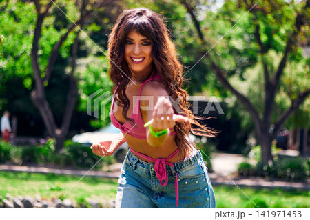 Beautiful mature brunette, Latina, Arab, getting ready and inviting others to dance, very cheerful, in an outdoor park. Wearing retro pink clothing and jeans, with makeup. Dancing with style, attitude Beautiful mature brunette, Latina, Arab, getting ready and inviting others to dance, very cheerful, in an outdoor park. Wearing retro pink clothing and jeans, with makeup. Dancing with style, attitude 141971453