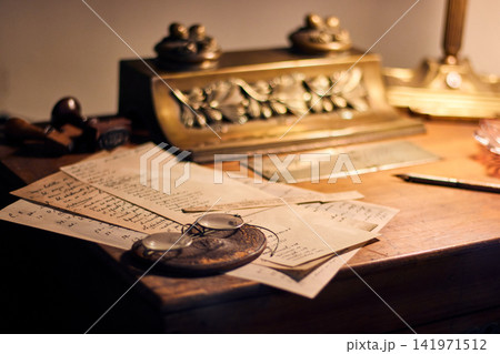 Details of old documents handwritten with quill and ink, resting on a desk, next to the author's antique glasses, illuminating the documents. History, antiquity, relics 141971512
