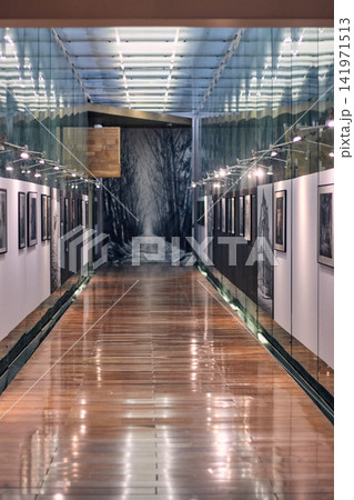 Well-lit corridor of a modern library, with its reflections, lights, glass, paintings on display, large scale and visible to the public. Well-lit corridor of a modern library, with its reflections, lights, glass, paintings on display, large scale and visible to the public. 141971513