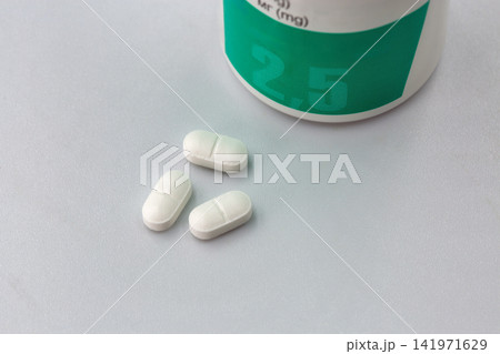 White pills and medicine bottle with 2.5 mg label, closeup. White pills and medicine bottle with 2.5 mg label, closeup. 141971629