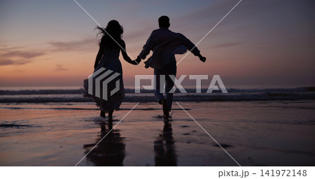 Couple, running and holding hands at beach with silhouette, travel and romantic date on holiday. Back, sunset and people at seashore with partner, celebration and tropical vacation for adventure trip Couple, running and holding hands at beach with silhouette, travel and romantic date on holiday. Back, sunset and people at seashore with partner, celebration and tropical vacation for adventure trip 141972148