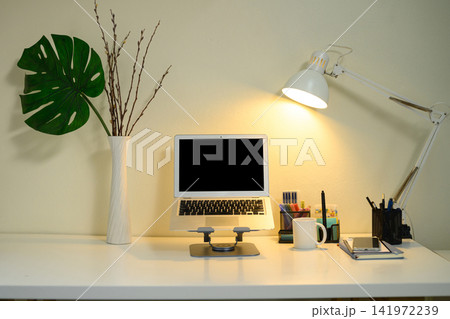 Clean Minimalist Home Office Desk Setup with Laptop, Desk Lamp, and Monstera Plant Decoration Clean Minimalist Home Office Desk Setup with Laptop, Desk Lamp, and Monstera Plant Decoration 141972239