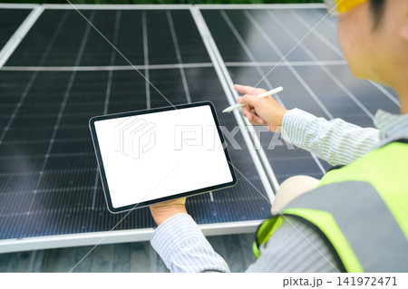 Engineer inspecting solar panels with digital tablet blank screen mockup at renewable energy installation site Engineer inspecting solar panels with digital tablet blank screen mockup at renewable energy installation site 141972471